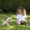 A young girl is playing with a stuffed dog on the grass in a garden. Anteprima dell’immagine prodotto