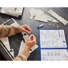 A person is assembling a 3D puzzle of the Millennium Falcon, with instructions and puzzle pieces laid out on a wooden table. Anteprima dell’immagine prodotto
