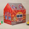 A children's play tent designed to look like a fire station, set up indoors on a wooden floor against a brick wall. Produktbild-Vorschau