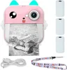 A pink mini instant camera with a cute cat design, printing a black and white photo of a child. Accessories like USB cable, lanyard, and paper rolls are also shown. Produktbild-Vorschau