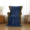 A dark blue blanket draped over a leather armchair in a room with natural light coming from a window. Produktbild-Vorschau