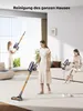 Three women are shown using cordless vacuum cleaners in a modern living room setting. Produktbild-Vorschau