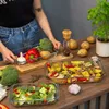 A person is preparing vegetables for cooking in glass baking dishes. Anteprima dell’immagine prodotto