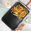 A baking tray with french fries on it, next to a salt shaker, eggshells, and wooden spoons. Voir les images du produit