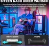 A young man playing a guitar while sitting in a gaming chair in a room with colorful lighting and shelves filled with gaming accessories. Produktbild-Vorschau