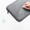 A hand is wiping water droplets off a gray laptop sleeve, demonstrating its water-resistant feature. Produktbild-Vorschau
