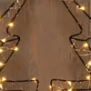 A close-up view of a wireframe Christmas tree decoration with warm white LED lights against a wooden background. Produktbild-Vorschau