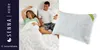 A couple is lying in bed, with a pillow displayed next to them. Podgląd zdjęcia produktu