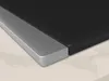 A close-up view of the corner of a black induction cooktop with a silver trim, resting on a marble-patterned surface. Voir les images du produit