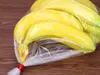 A bunch of bananas in a clear plastic bag, tied with a red twist tie, resting on a wooden surface. Náhled obrázku produktu