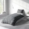 A bedroom scene with a bed dressed in geometric patterned bedding. Produktbild-Vorschau
