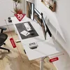 A white standing desk with multiple monitors, a keyboard, mouse, and glasses on it. The desk is shown in a home office setting with a chair and a window in the background. Podgląd zdjęcia produktu