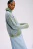 A woman wearing a sweater and skirt against a white background. Produktbild-Vorschau