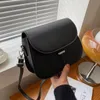 A black leather handbag is displayed on a wooden surface with blinds in the background. Náhľad obrázku produktu