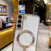 A close-up view of a white phone case with gold accents, showing the camera lenses and a magnetic ring for MagSafe. Náhled obrázku produktu