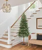 A Christmas tree is placed next to a staircase and a wicker bench in a home. Anteprima dell’immagine prodotto