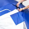 A close-up shot of a person's hands securing a clip on a blue and white umbrella or beach shelter. Anteprima dell’immagine prodotto