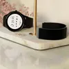 A smartwatch and its band are displayed on a marble surface, with a blurred floral background. Anteprima dell’immagine prodotto