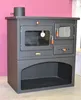 A dark gray wood-burning stove with a glass oven door and a storage compartment below, set against a pink wall. Produktbild-Vorschau
