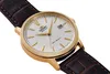 A close-up, angled shot of a gold-toned watch with a white face and a brown leather strap. Náhled obrázku produktu