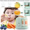 A baby is being fed baby food from a spoon, with a baby food maker, carrots, and blueberries shown in the foreground. The background includes instructional graphics and close-ups of the baby food maker. Produktbild-Vorschau