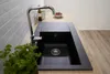 A black kitchen sink with a chrome faucet is shown on a wooden countertop, with a tiled backsplash behind it. Produktbild-Vorschau