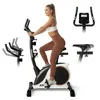 A woman is using a stationary exercise bike. Insets show close-ups of the handlebars and seat. Produktbild-Vorschau