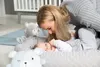 A mother is interacting with her baby in a baby lounge with stuffed animals. Anteprima dell’immagine prodotto
