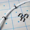A white pipe with black clips is laid on a grid-like surface. Náhľad obrázku produktu