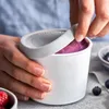 A person is opening a white ice cream container filled with purple ice cream. Produktbild-Vorschau
