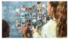 Two people are looking at a wall covered in photos, one person is holding a camera. Anteprima dell’immagine prodotto