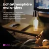 A person wearing headphones is relaxing on a couch, with a bottle lamp on a coffee table in the background. Anteprima dell’immagine prodotto