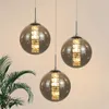Three glass pendant lights with gold accents hanging against a light background. Produktbild-Vorschau