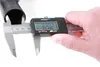 A hand holds a digital caliper measuring a black cylindrical object. Produktbild-Vorschau
