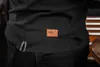 A close-up shot of the lower back of a person wearing a black t-shirt with a brown leather tag that has the 'NEO TOOLS' logo on it. Produktbild-Vorschau