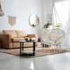 A cozy living room with a tan sofa, a hanging chair, and a coffee table. Voir les images du produit