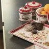 A festive arrangement of Christmas-themed ceramic containers and cookies on a dark countertop. Náhľad obrázku produktu