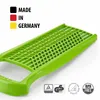A close-up of a green grater with text and certification logos in the background. Produktbild-Vorschau
