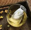 A tea bag steeping in a glass of tea, surrounded by dried ingredients on a wooden tray. Anteprima dell’immagine prodotto