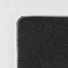 A close-up view of the corner of a rug, showing the textured white top and the black, dotted underside. Náhled obrázku produktu