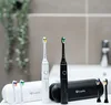 Two electric toothbrushes, one white and one black, are displayed on a bathroom counter with their charging cases and extra brush heads. Anteprima dell’immagine prodotto