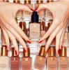 Hands forming a heart shape over bottles of Estee Lauder Double Wear foundation. Náhled obrázku produktu