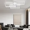 A modern living room with a sectional sofa, fireplace, and a large abstract painting on the wall. A contemporary ceiling light fixture is prominently displayed. Produktbild-Vorschau