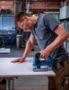 A man is using a jigsaw to cut a piece of material in a workshop. Anteprima dell’immagine prodotto