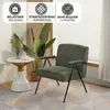 A green armchair is placed next to a small white and gold side table, with a large plant in the background and a window with blinds. Produktbild-Vorschau