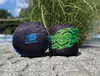 Two stuffed punching bags are placed on a stone surface in front of a green plant. A swimming pool is visible in the background. Produktbild-Vorschau