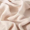 A close-up view of beige muslin fabric, showing its textured weave and soft folds. Podgląd zdjęcia produktu