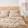 A neatly made bed with taupe musselin bedding and two woven rattan headboards. Produktbild-Vorschau