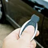 A hand holding a car key fob in front of a car. Produktbild-Vorschau