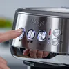 A close-up shot of a person's finger pressing a button on a Sage espresso machine. Produktbild-Vorschau